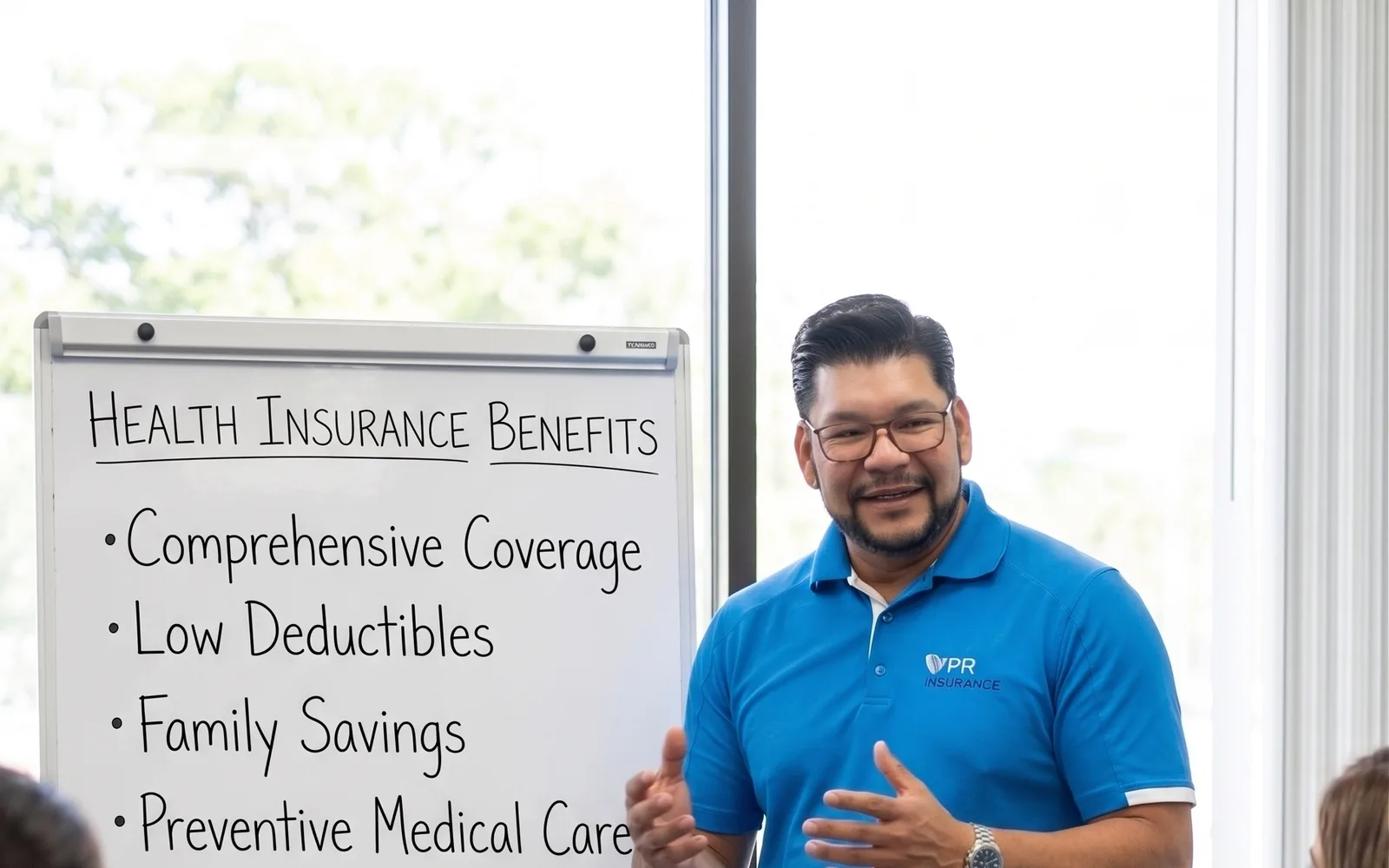 A presenter reviewing a whiteboard listing health insurance benefits with colleagues in a meeting